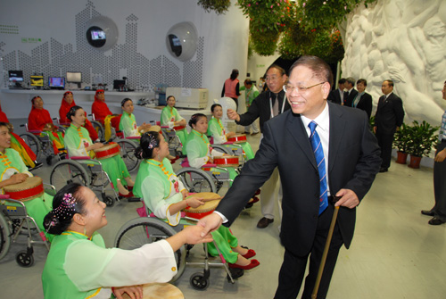 圖為中國殘聯(lián)黨組書記、理事長王新憲與寶山區(qū)輪椅鑼鼓隊(duì)隊(duì)員們親切握手